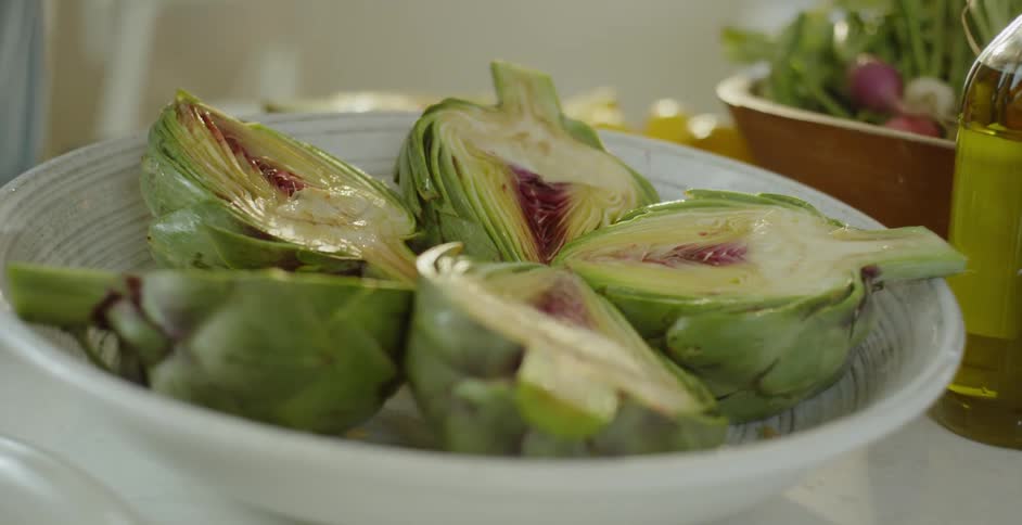 A woman squeezes juice on artichokes on a plate