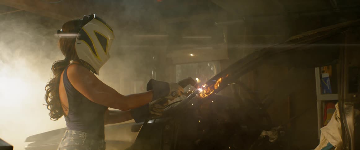 A woman welds the steel frame of a car