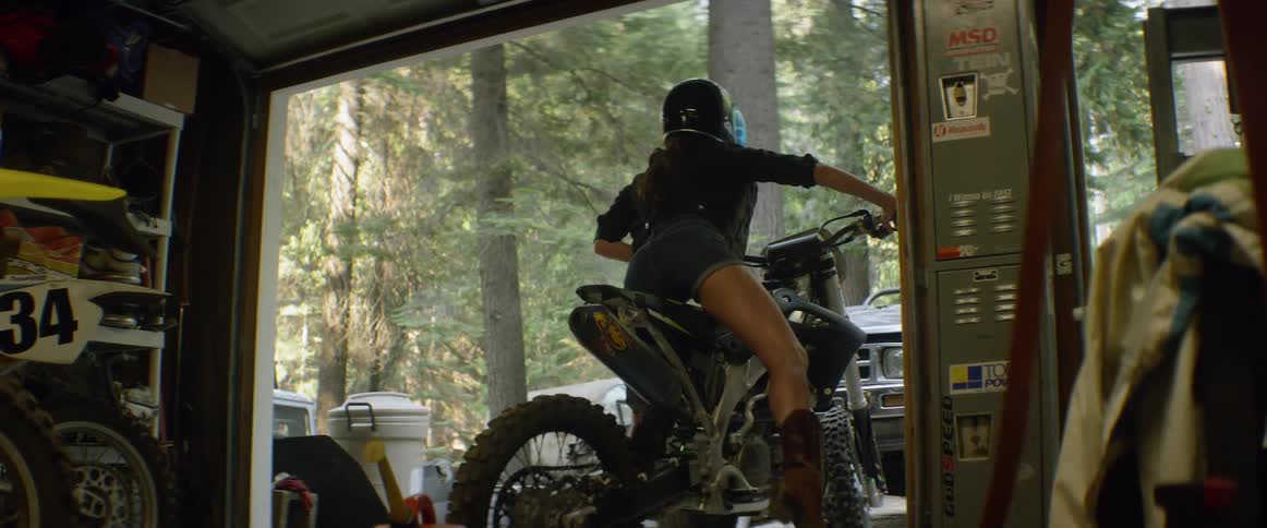 Woman wearing a helmet gets on a motorcycle