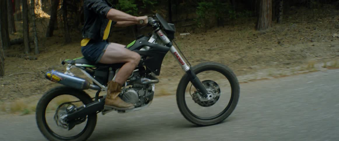A woman rides a dirt bike on a forest trail