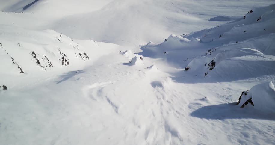 Snow is rushing down a hill as a skier speeds past