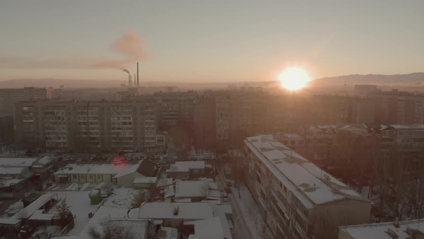 The sun sets over a snowy city