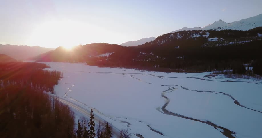 The sun sets over a snowy mountain range