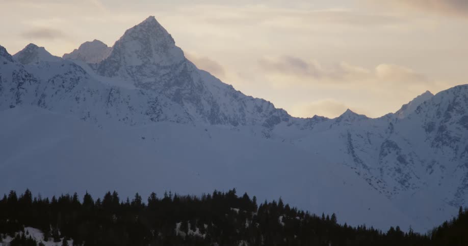 Clouds hang above a snow covered mountain