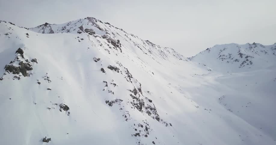 Snow is covering the slopes of a mountain range during the day