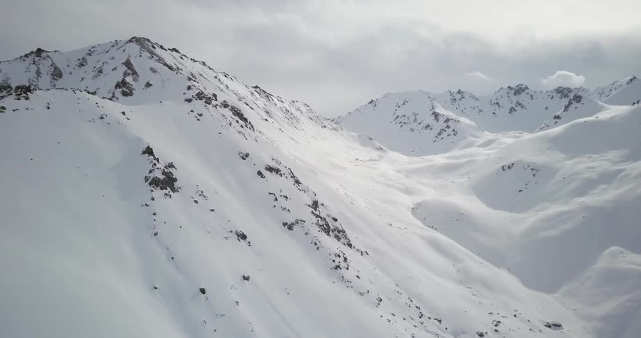 White clouds hang above snow covered mountains