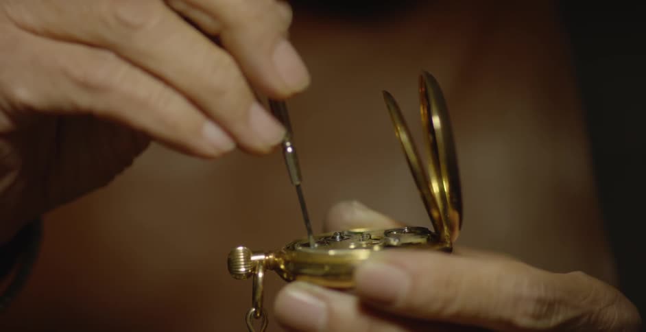 Someone is using a small screwdriver to fix a pocket watch