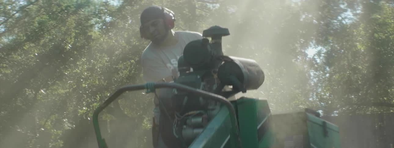 A man operates machinery outside on a sunny day