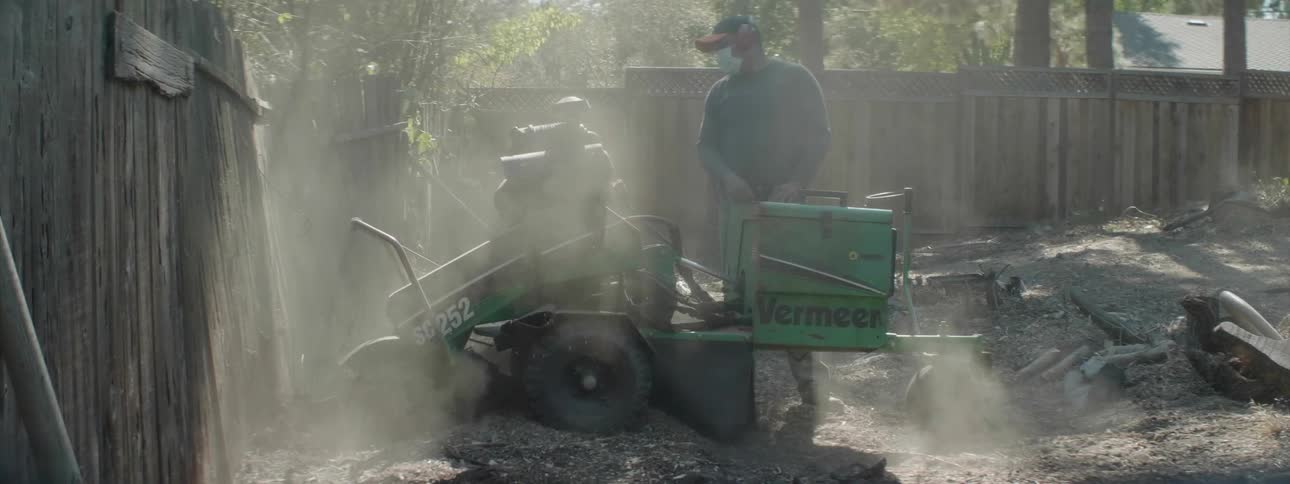 Man uses a tiller over rocky ground on a sunny day