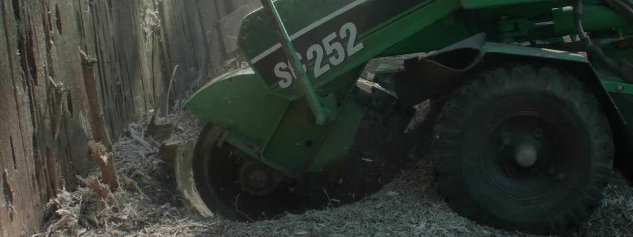 A stump grinder is grinding away a tree stump in a yard during the day