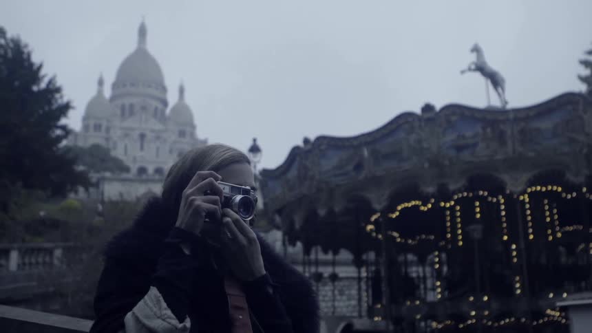 A woman takes a photograph near a carousel