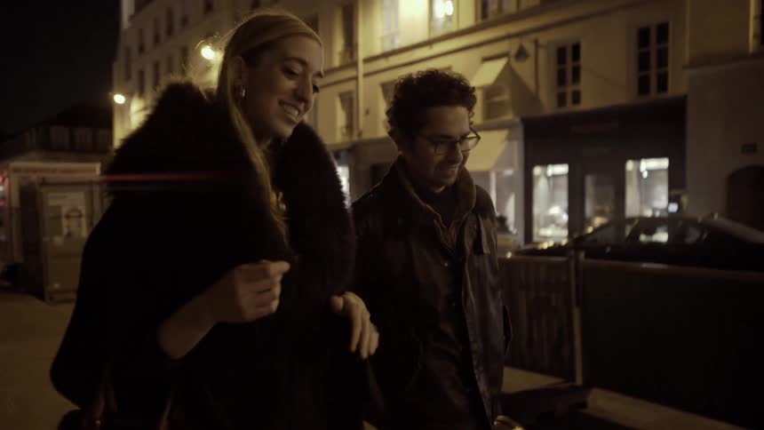 A man and woman walk together outside at night