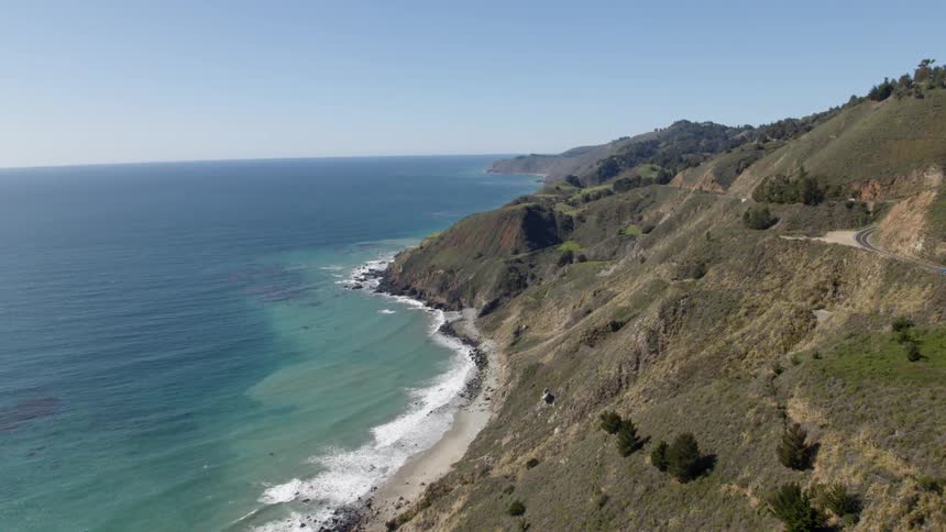 Ocean waves roll into mountainous shore