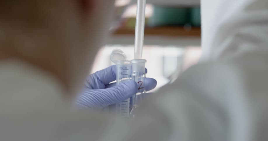 A scientist is putting liquid into a vile