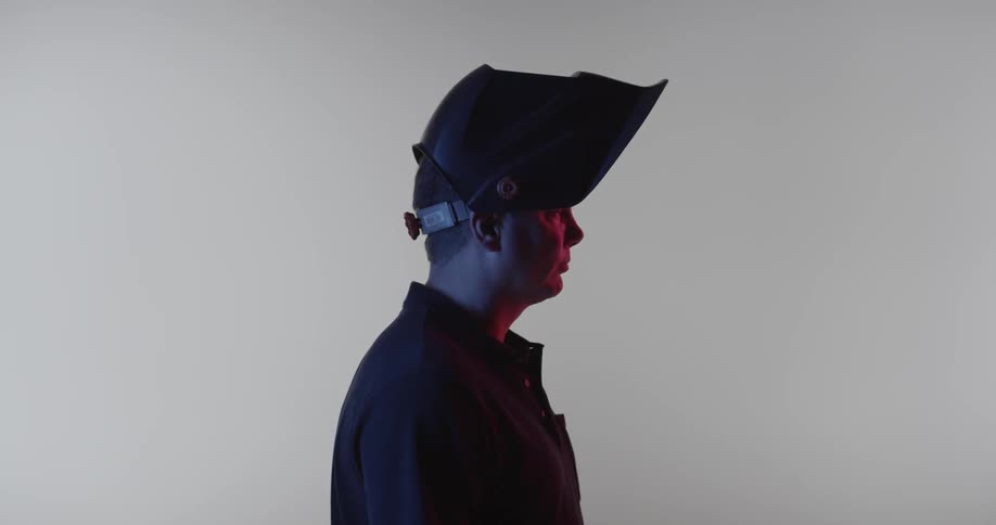 A welder wears a mask while standing still