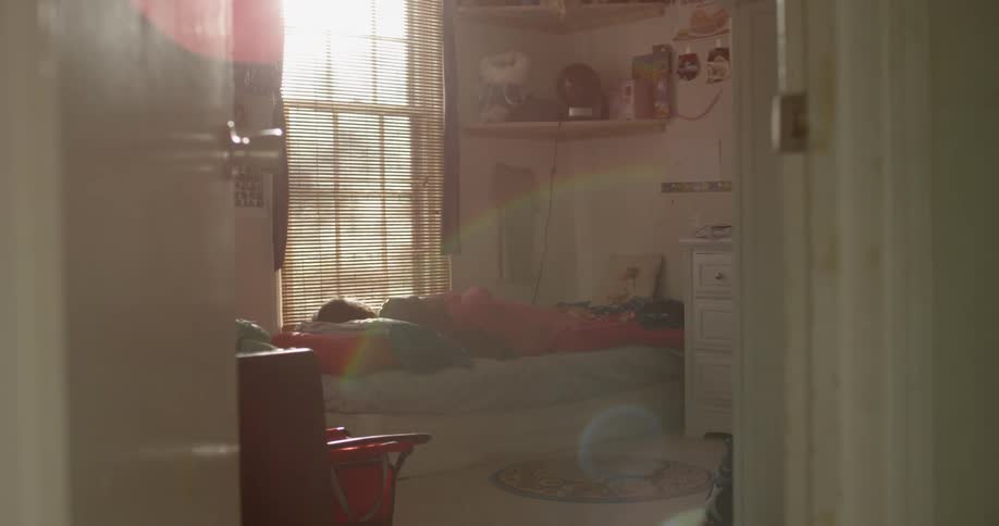 Girl lays in bed and looks out window