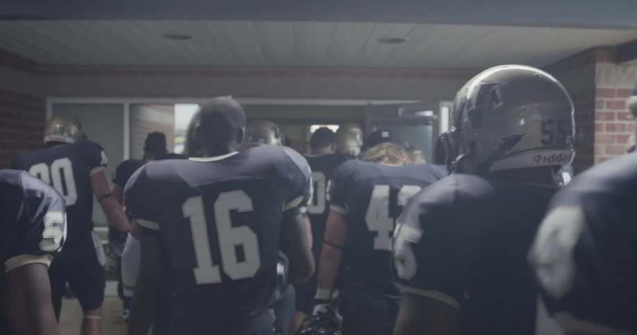 A team of football players are walking into a building