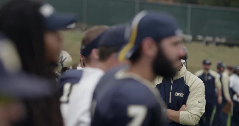 Football players are lined up on the sidelines