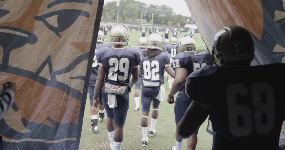 Football players are leaving the locker room and going onto the field