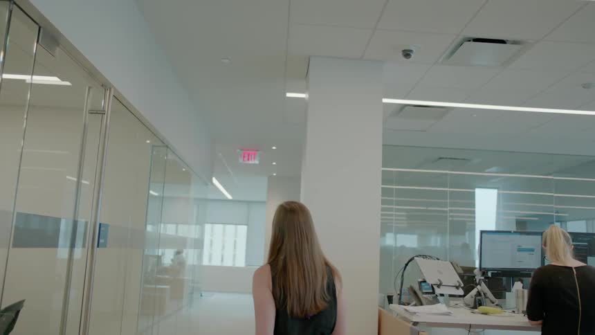 A woman is walking through an office during the day