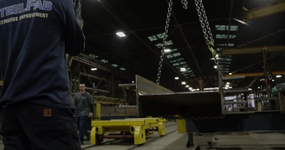 A man works with chains in steel warehouse