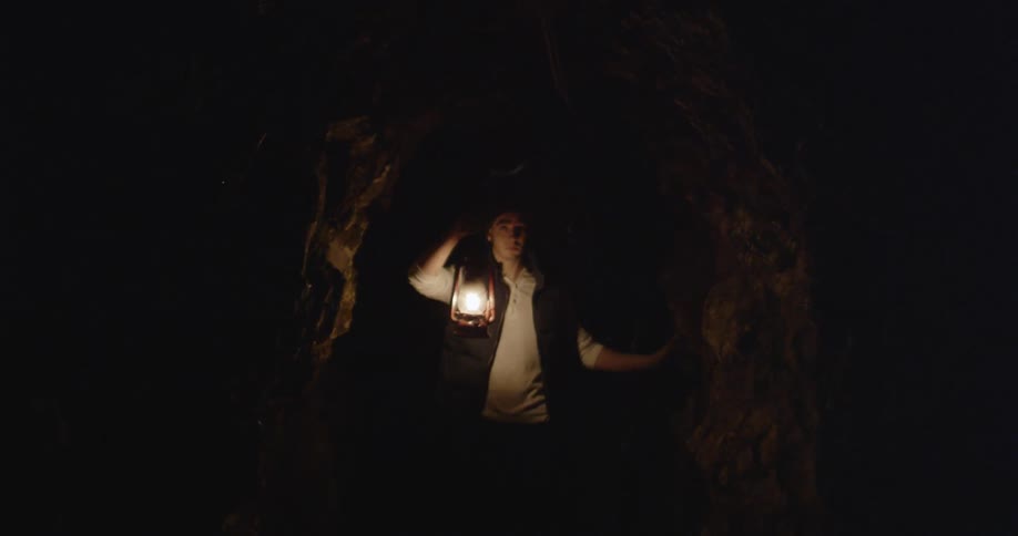 A man with a lantern is walking through a cave