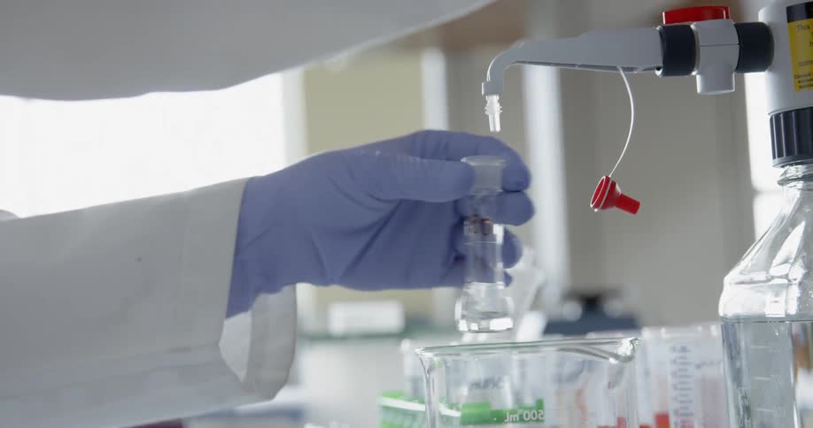 A scientist in a lab is filling vials with a liquid