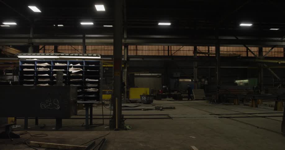 The warehouse is dark and empty besides one person pushing a cart