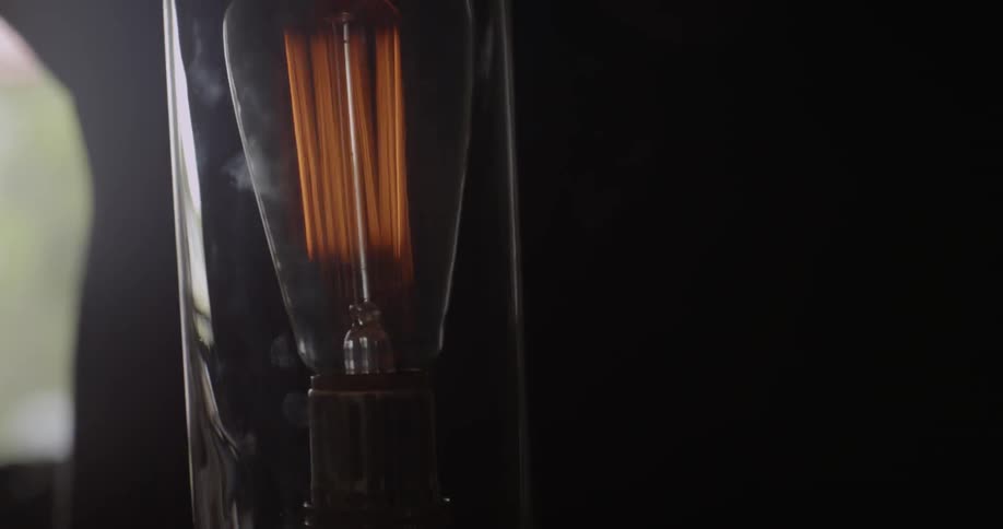 A person is putting a lightbulb into a lamp inside during the day