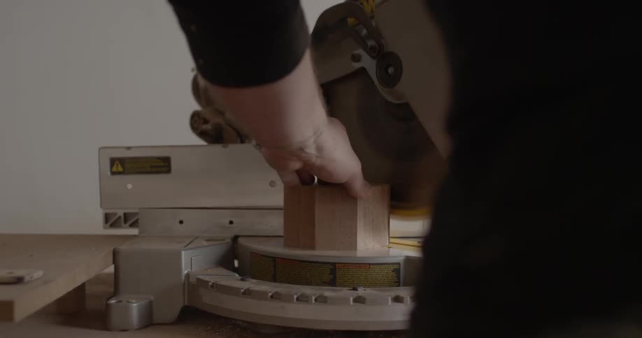 A man cuts a piece of wood with a miter saw