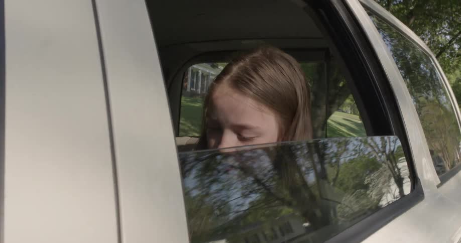 Girls rides in back seat of car with window rolled down