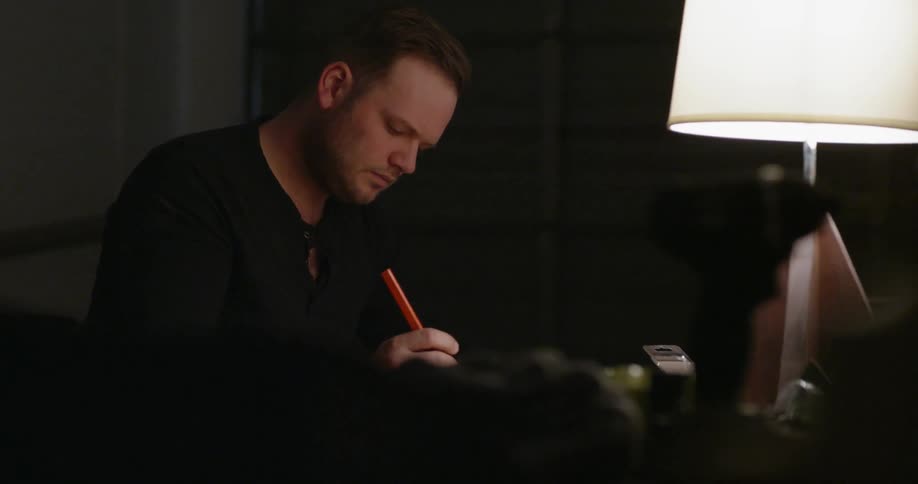 A man writes while sitting at a desk