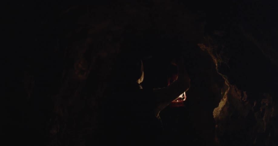 A man with a lantern is making his way through a cave