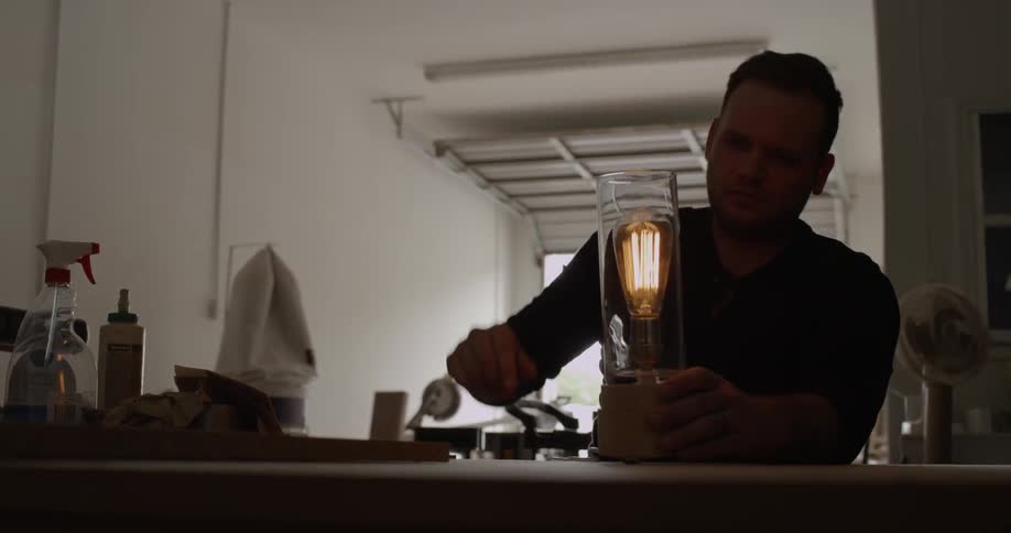 A man screws in an edison style bulb in a lamp