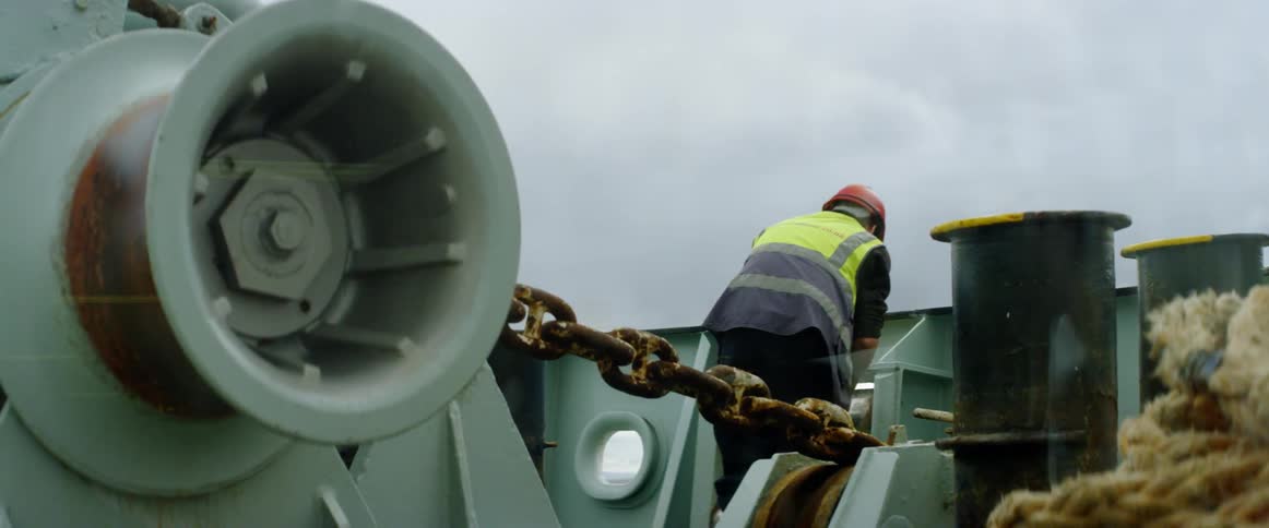 A man is working on a boat pulling rope up