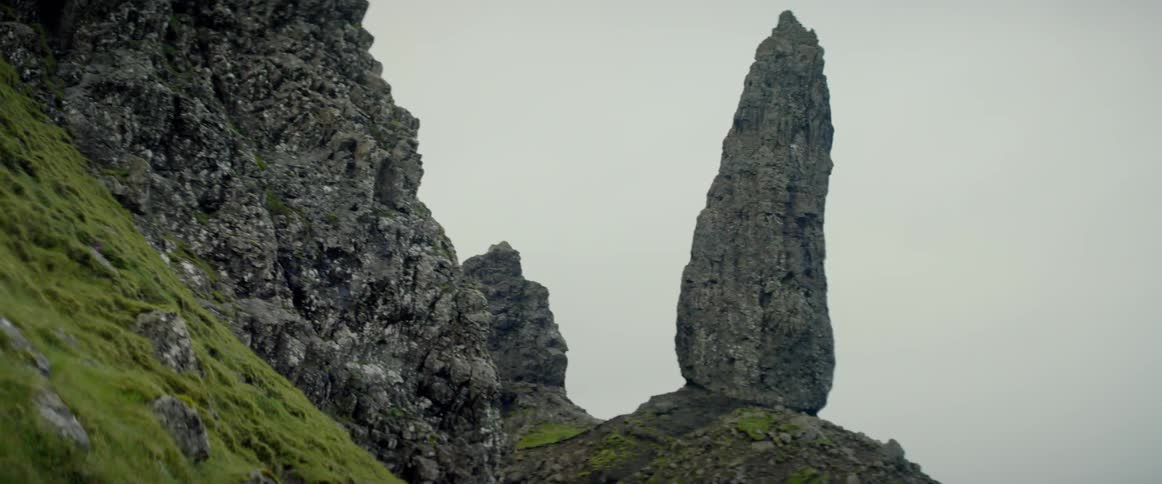 A tall and thin rock formation is perched atop a hill