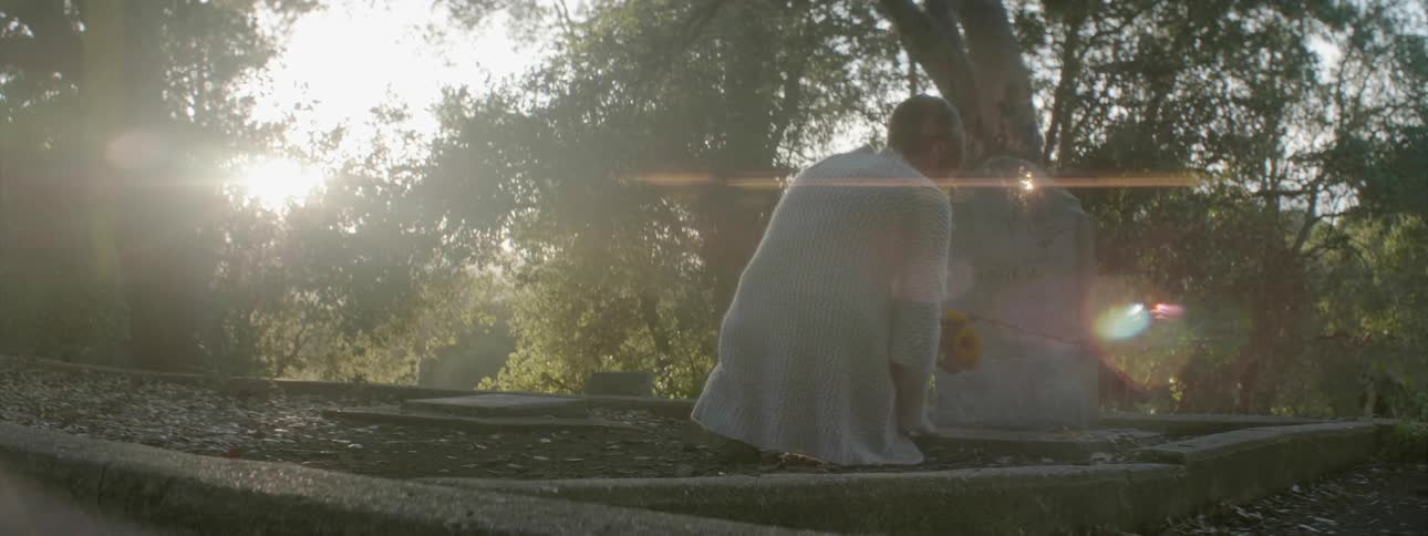 A woman puts flowers in front of a headstone