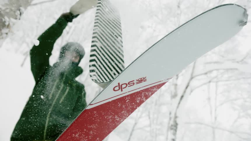 A skier pulls a climbing skin off a ski