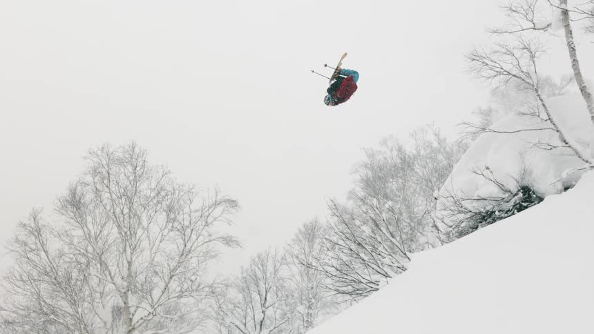 Skier flipping high in the air on a steep hill