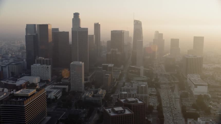 Cars drive down the road through the city at sunset