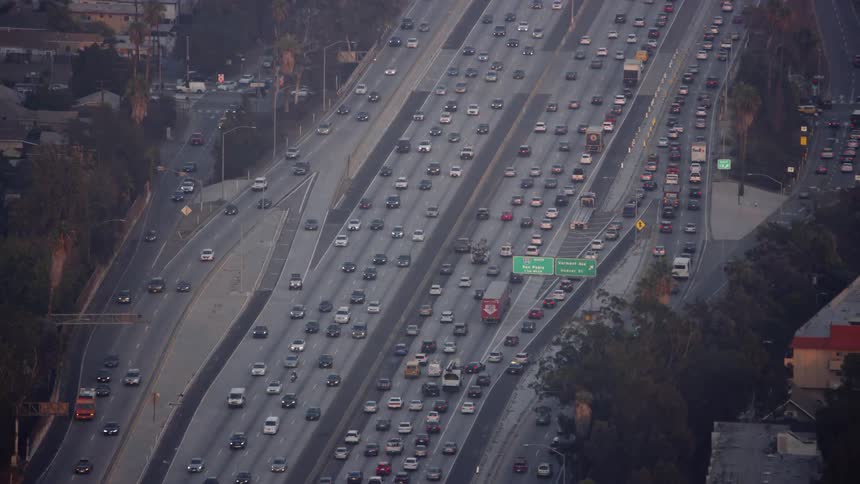 Cars drive on a city highway at sunset