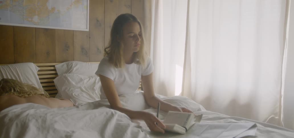 A woman is finishing up writing in her journal in the morning in bed