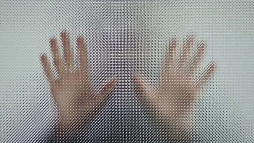Person placing their hands on a piece of material that has a rough and somewhat opaque surface