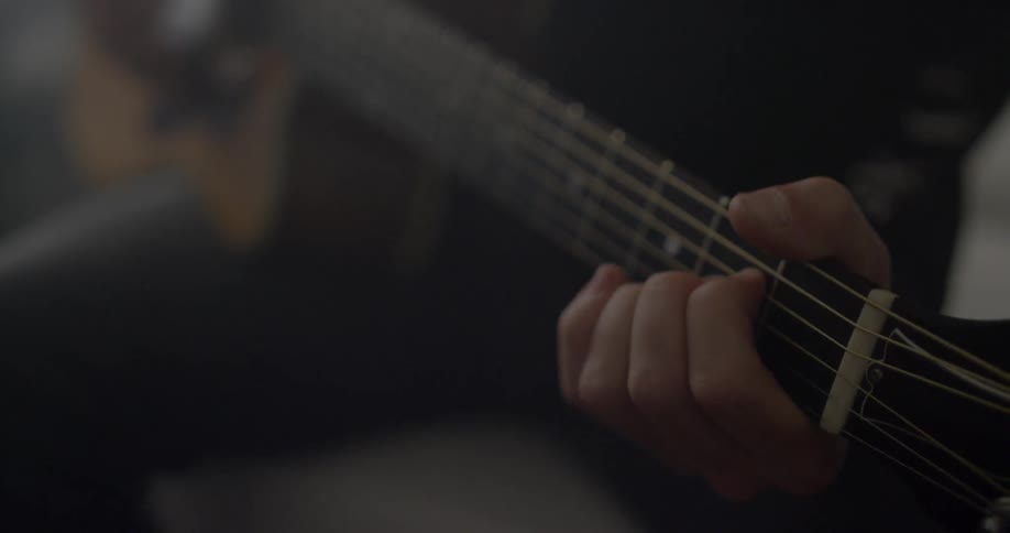 A person sitting down plays the guitar