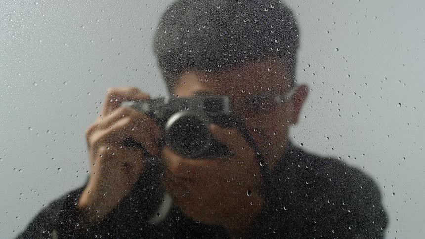 A young man takes a photograph with a camera