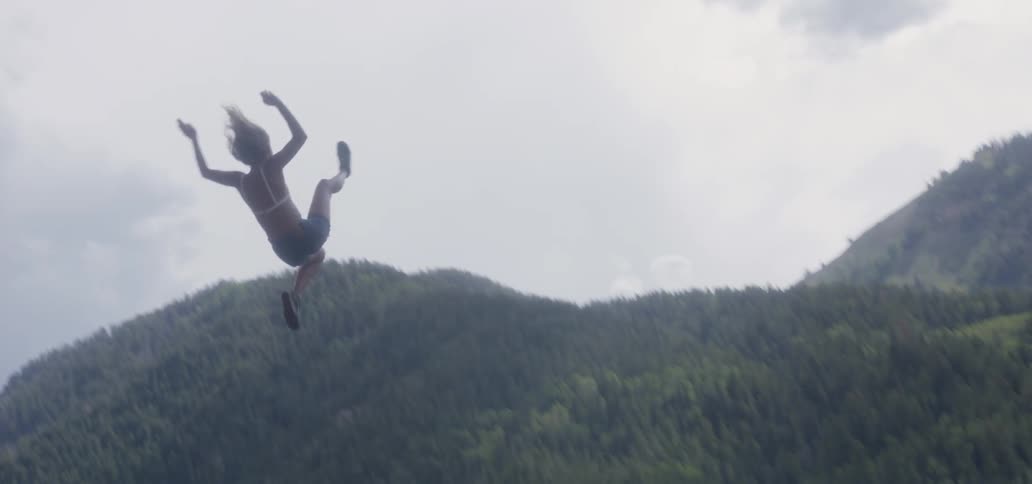 A woman swings and jumps into a lake