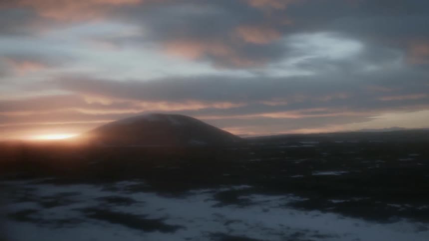Sunlight peaks around a hill in the dark landscape