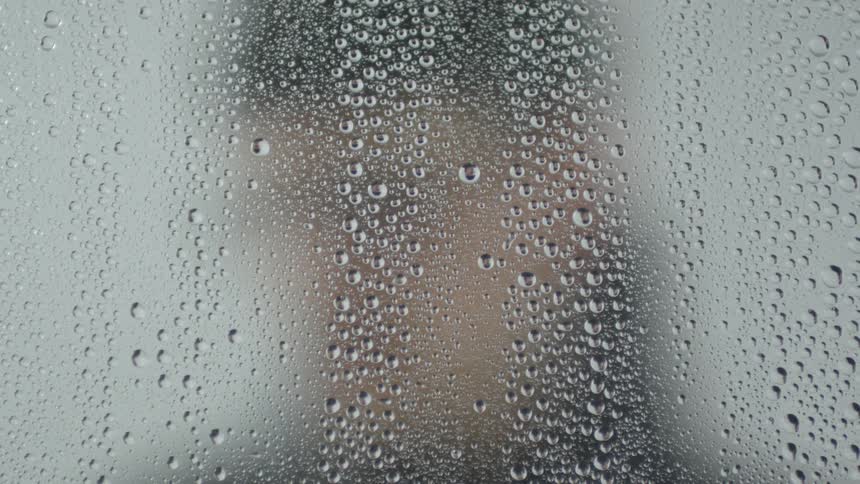 A man stands by a foggy and moist window