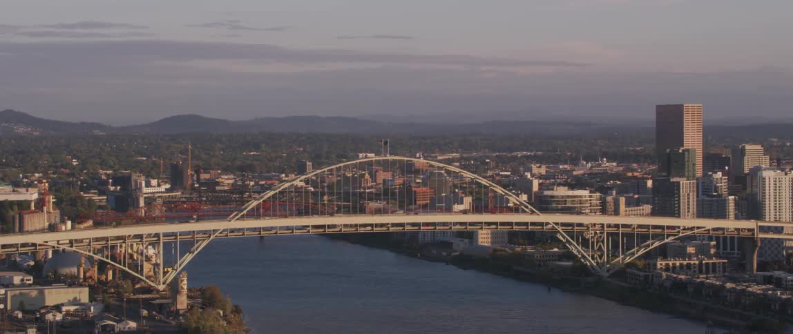 Traffic is moving across a bridge over a river during daylight