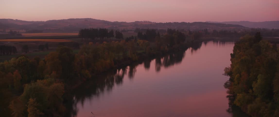 The sun sets over a rural river